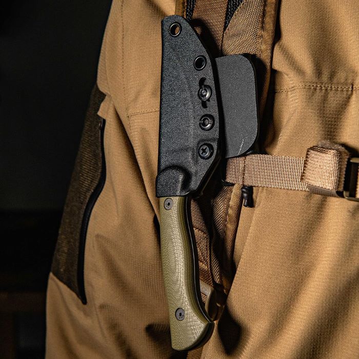 Montana Knife Company - The Blackfoot Fixed Blade 2.0 - Olive - knife inside black kydex sheath strapped on a backpack strap on the front chest of a person wearing an outdoor technical jacket