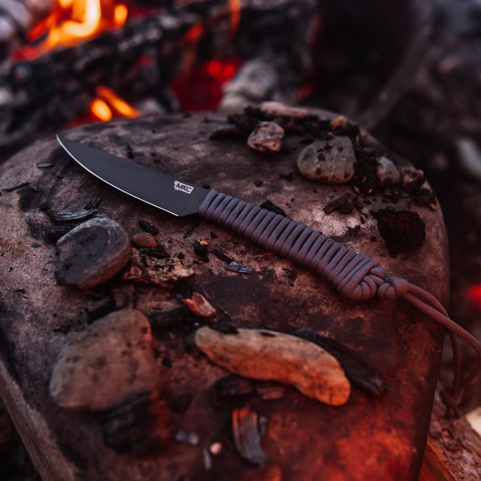 Montana Knife Company - The Speedgoat Fixed Blade - Grey - Knife laying on rock in front of fire next to small stones and charred wood pieces